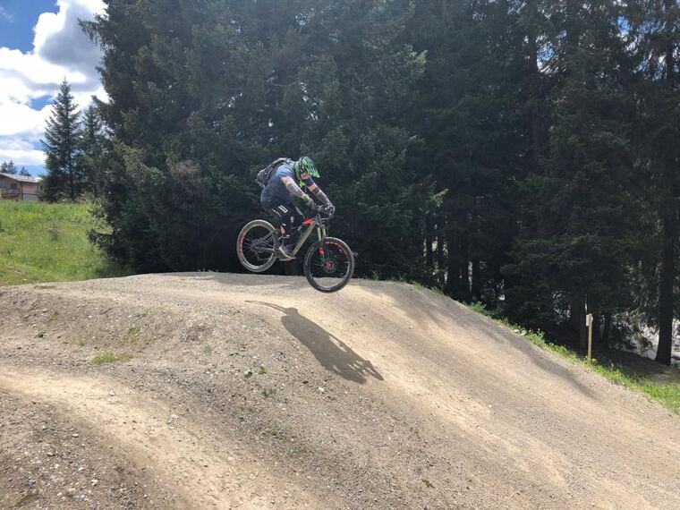 Biker im Sprung über einen Erdhügel im Bikepark