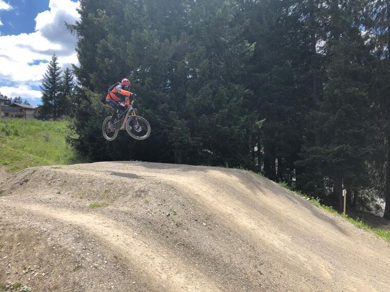 Biker in roter Jacke im Sprung im Bikepark